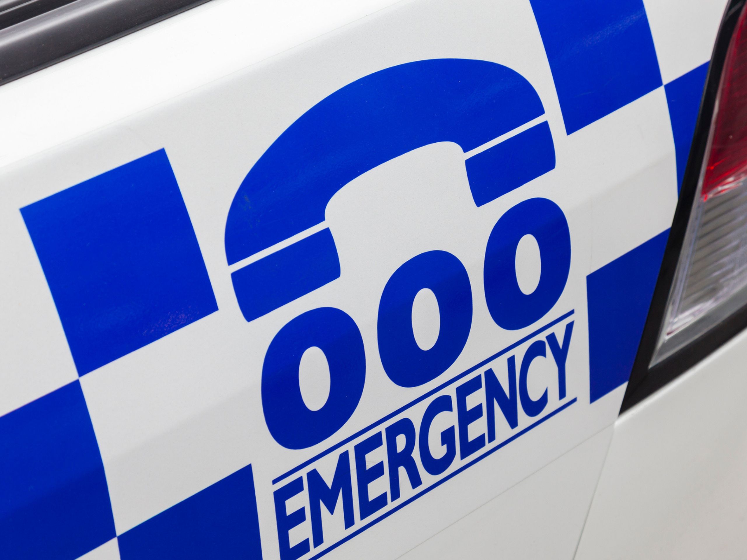 Sign on side of police car with working 000 emergency