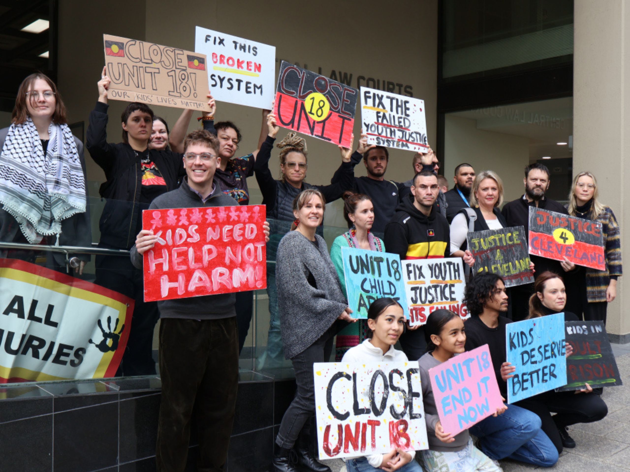 Advocates holding signs outside law courts calling to close Unit 18 youth prison